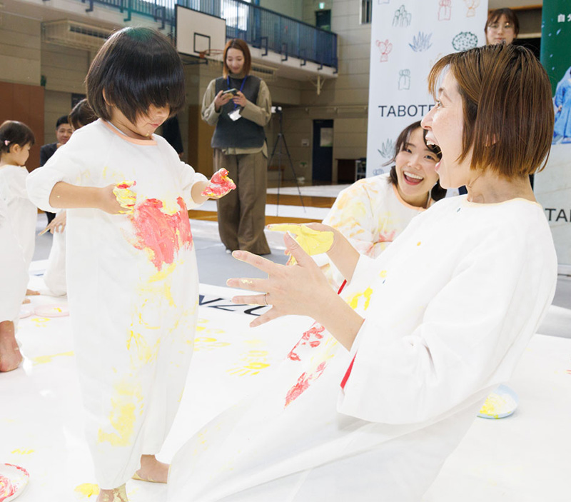 かぞくのおえかきウェアを着用している親子が楽しそうに絵の具で遊んでいる写真