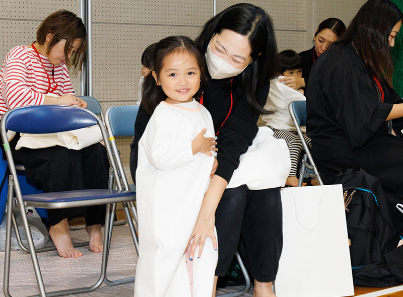 イベント会場にいるかぞくのおえかきウェアを着用した親子の写真