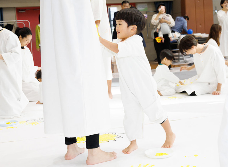 かぞくのおえかきウェアを着用し、ゆびえのぐで遊んでいる親子の写真