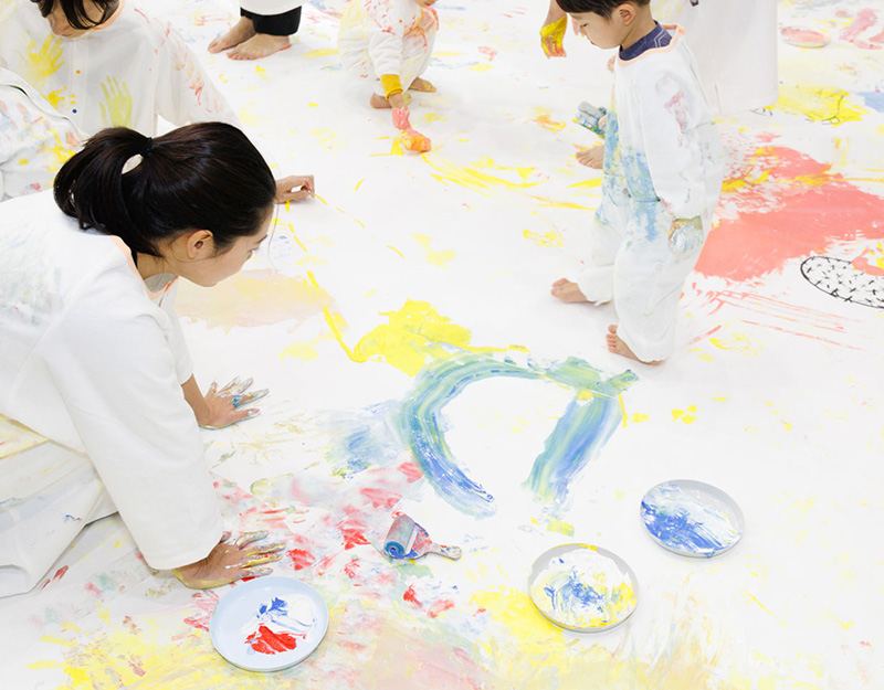 かぞくのおえかきウェアを着用し、ゆびえのぐで遊んでいる親子の写真