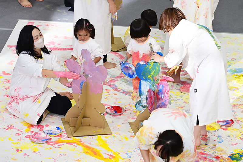 かぞくのおえかきウェアを着用し、ゆびえのぐで遊んでいる親子の写真