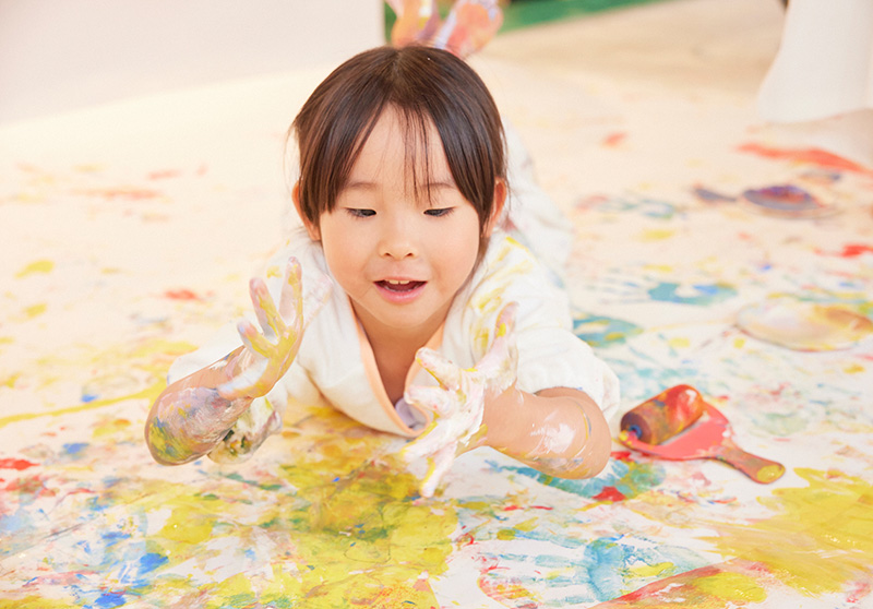 かぞくのおえかきウェアを着てえのぐあそびを楽しんでいる子供