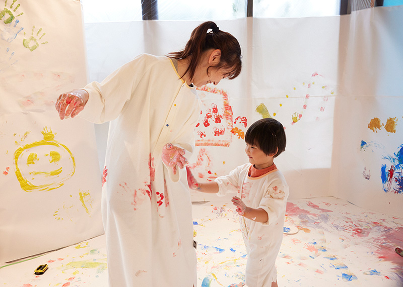 かぞくのおえかきウェアを着てえのぐあそびを楽しんでいる親子