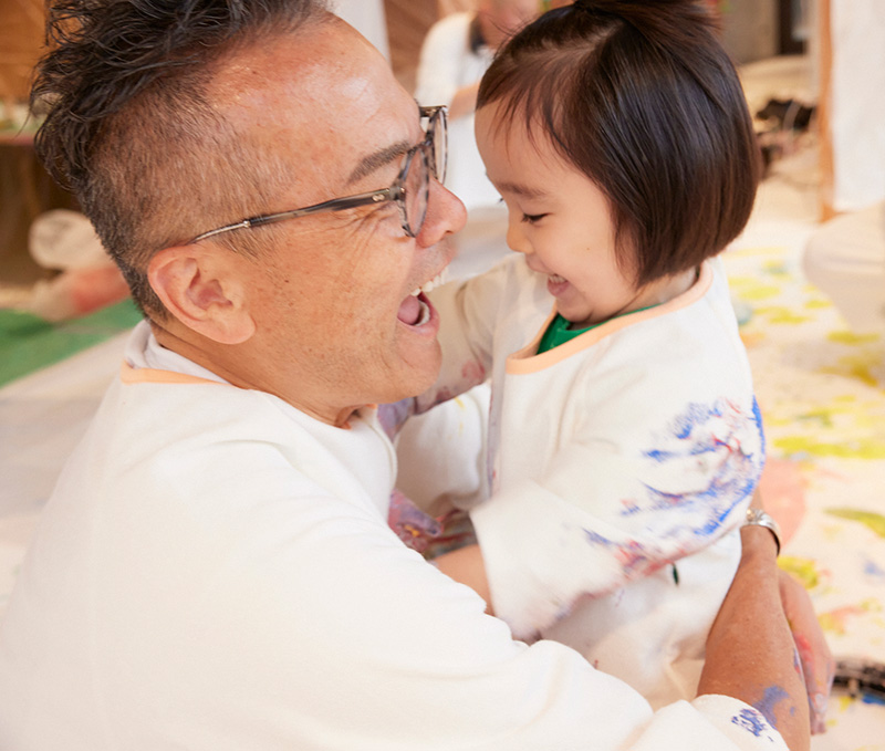 かぞくのおえかきウェアを着てえのぐあそびを楽しんでいる親子