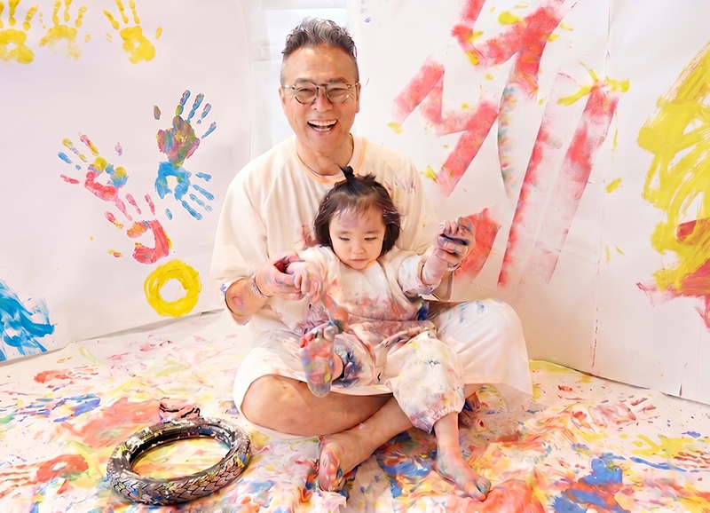 かぞくのおえかきウェアを着てえのぐ遊びを楽しんでいる親子