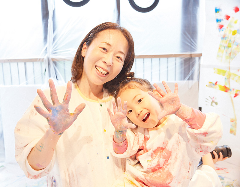 かぞくのおえかきウェアを着てえのぐ遊びを楽しんでいる親子