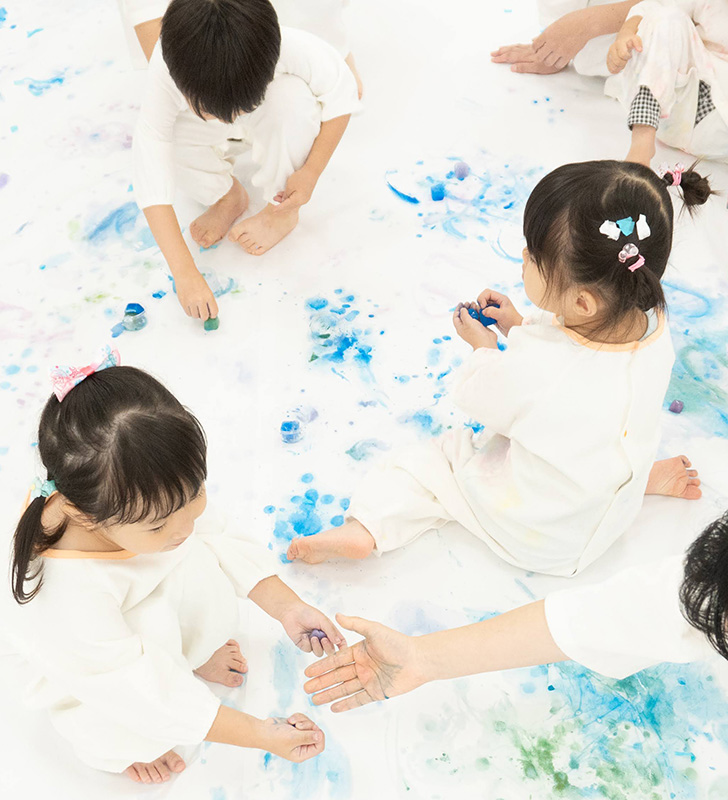 色水氷を模造紙に垂らして絵を描く親子の写真